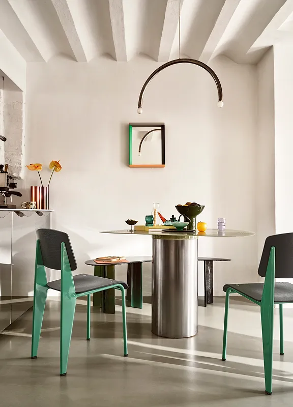 Moderner Essbereich mit zwei Vitra Standard Chairs in Grün, runder Tisch mit Edelstahlfuß und halbkreisförmiger Pendelleuchte.